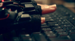 A gloved hand typing on a keyboard