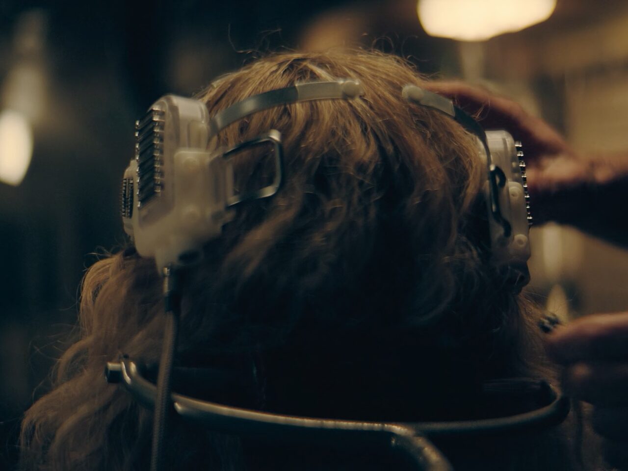 Rear view of Chloë Grace Moretz as Flynne Fisher using a futuristic VR headset with direct neural interface. As seen in The Peripheral (2022)